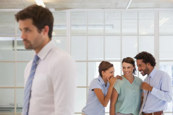 Colleagues gossiping behind a sad businessman