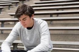 Depressed teen sitting alone on bleachers.