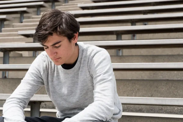Depressed teen sitting alone on bleachers.