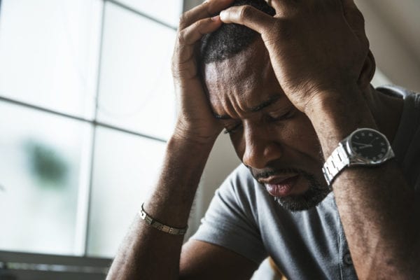 Young man showing stress with hands on his head.