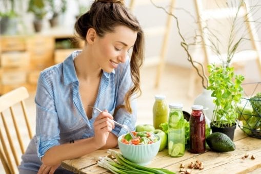 Young woman at table eating a salad.
