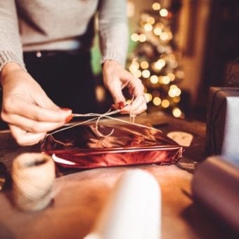 Woman wrapping holiday gift with a ribbon.