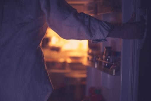Woman opening refrigerator at nighttime.