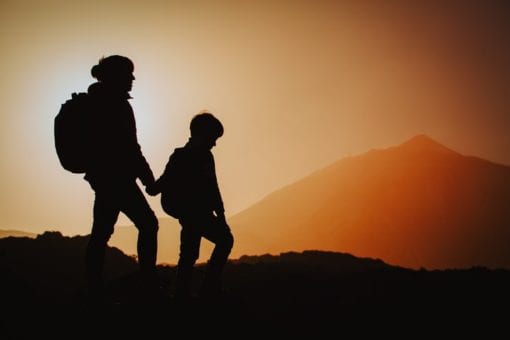 Mom walking with son on mountain during sunset.
