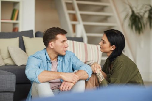 Young couple having meaningful conversation in living room.